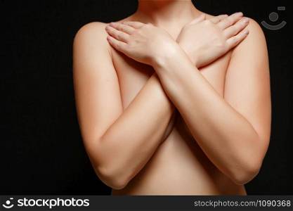 naked young brunette woman covers her Breasts. on black isolated background