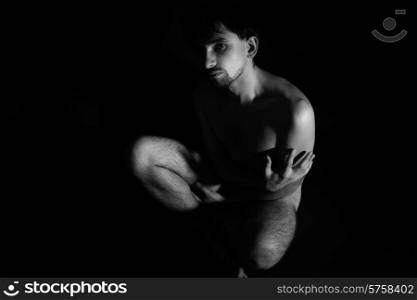 Naked young handsome man sitting on the floor