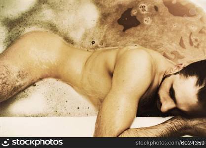 Naked young handsome man takes a bath