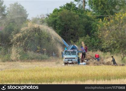 NAKHON PHANOM, THAILAND - NOVEMBER 11, 2018: Farm workers milling rice with a threshing machine on a car