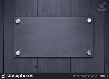 nameplate at black wooden background texture surface, with screws
