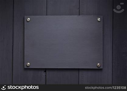 nameplate at black wooden background texture surface, with screws