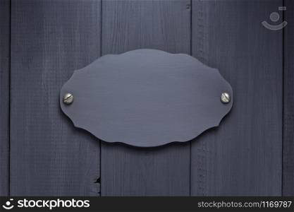 nameplate or wall sign at black wooden background texture surface, with screws