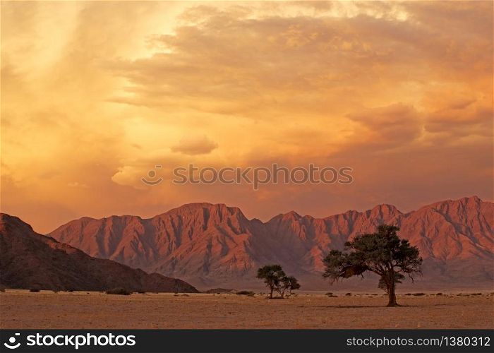 Namib desert landscape at sunset with rugged mountains and dramatic clouds, Namibia
