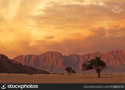 Namib desert landscape at sunset with rugged mountains and dramatic clouds, Namibia