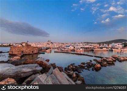 Naousa town - main tourist attraction in Paros island, Cyclades. Harbor with ancient stone Venetian Castle for surveilling the Aegean Sea. Beautiful sunset in old port with boats. Greece paradise