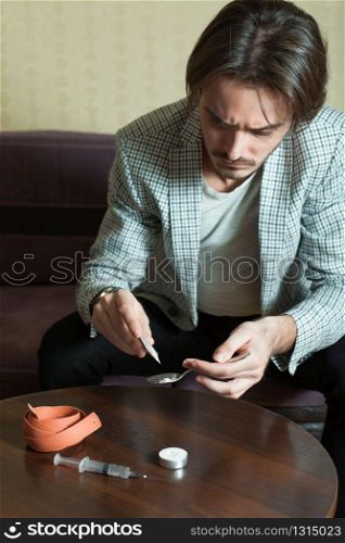 Narcotic dependence man preparing a dose of heroin for injection. Narcotic dependence man preparing a dose of heroin