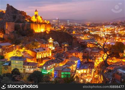 Narikala and Old town at sunset, Tbilisi, Georgia. Amazing View of Narikala ancient fortress with St Nicholas Church, Jumah Mosque, Sulphur Baths and famous colorful balconies in old historic district Abanotubani in night Illumination at sunset, Tbilisi, Georgia.