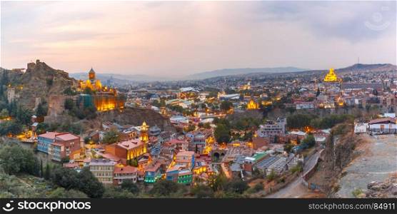 Narikala and Old town at sunset, Tbilisi, Georgia. Amazing panoramic view of Narikala ancient fortress and Sameba Holy Trinity Cathedral, Metekhi Church, bridge of Peace and Presidential Palace in old historic district Abanotubani in night Illumination at sunset, Tbilisi, Georgia.