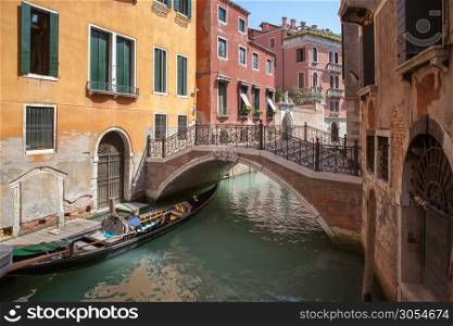 Narrow canal among old colorful brick houses in Venice, Italy. Beautiful bridge in antique Venice city, Italy.. Venice canal scene in Italy