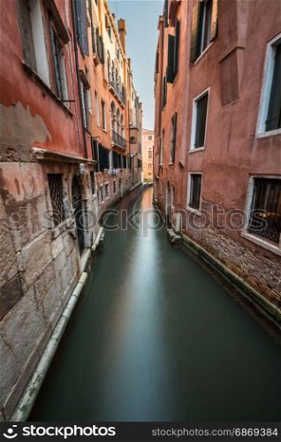 Narrow Canal Among Old Colorful Brick Houses in Venice, Italy