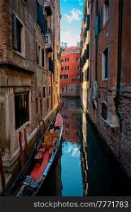 Narrow canal between colorful old houses with gondola boat in Venice, Italy. Narrow canal with gondola in Venice, Italy