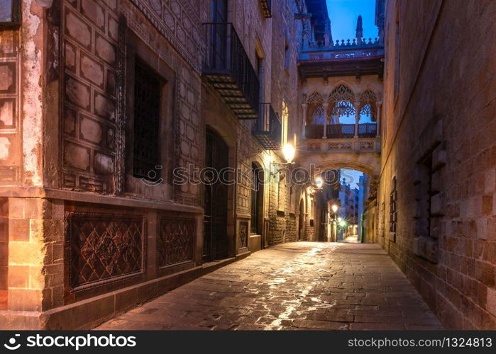 Narrow cobbled medieval Carrer del Bisbe street with Bridge of Sighs in Barri Gothic Quarter in the morning, Barcelona, Catalonia, Spain. Bridge of Sighs in Gothic Quarter, Barcelona