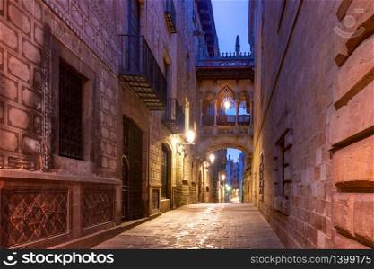 Narrow cobbled medieval Carrer del Bisbe street with Bridge of Sighs in Barri Gothic Quarter in the morning, Barcelona, Catalonia, Spain. Carrer del Bisbe in Gothic Quarter, Barcelona