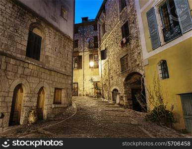 Narrow cobbled street in old town Peille at night, France.