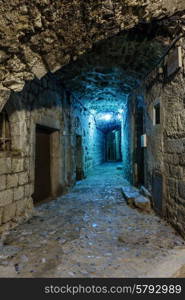 Narrow cobbled street in old town Peille at night, France.