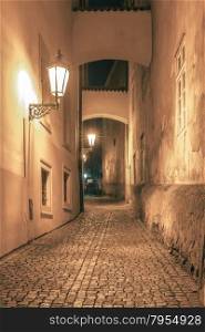 Narrow cobbled street of the old town at night in Mala Strana, Prague, Czech Republic. Toning in cool tones