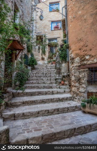 Narrow cobbled street with flowers in the old village Tourrettes-sur-Loup , France.