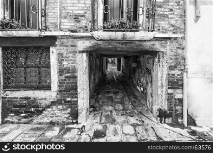 Narrow passage between old houses in Venice. Street with archway in the medieval italian town. Black and white picture
