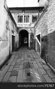 Narrow passage between old houses in Venice. Street with archway in the medieval italian town. Black and white picture