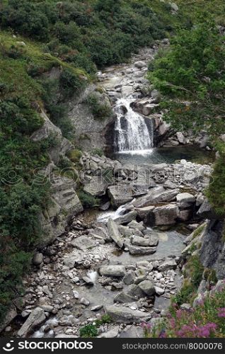 Narrow river with small waterfall near Gotthardpass in Switzerland