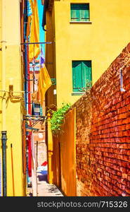 Narrow side street between old yellow houses in Burano, Venice, Italy