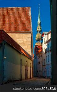 Narrow street of Old Town on a sunny day, Saint Peter church on the background, Riga, Latvia