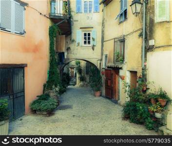 Narrow street with flowers in the old town Coaraze in France. Toned