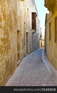 Narrow street with traditional maltese buildings in historical part of Mdina. The city was founded as Maleth in around the 8th century BC by Phoenician settlers on the island of Malta