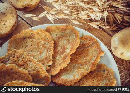 "National Belarusian dish - potato pancakes "draniki" close-up on a linen background. Potato pancakes on a plate and fork on linen background"