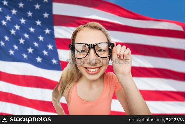 national, education and people concept - happy smiling young woman or teenage girl eyeglasses over american flag background