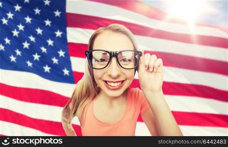 national, education and people concept - happy smiling young woman or teenage girl eyeglasses over american flag background. happy young woman or teenage girl in eyeglasses