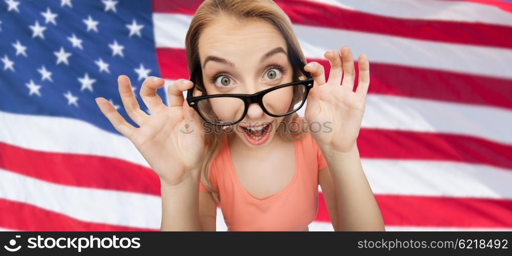 national, education and people concept - happy surprised young woman or teenage girl eyeglasses over american flag background