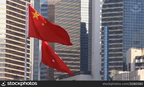 National flag of People&acute;s Republic of China and flag of Hong Kong waving in the wind over modern building background. The wind fluttering flags of China and Hong Kong, Special Administrative Region of China. Hong Kong, November 9 ,2017.