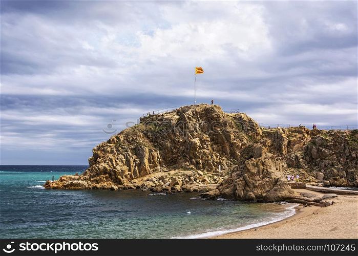 National flag of Spain on the rock Sa Palomera Spain, Blanes)