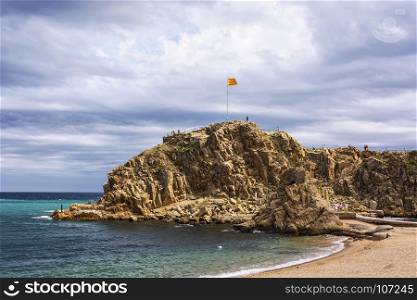 National flag of Spain on the rock Sa Palomera Spain, Blanes)