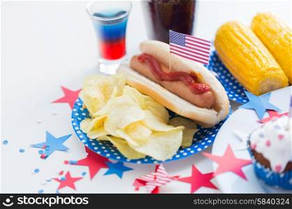 national holidays, celebration, food and patriotism concept - close up of hot dog with american flag decoration, potato chips and drinks on 4th july at party on independence day