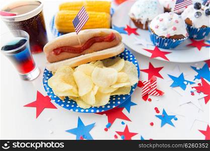 national holidays, celebration, food and patriotism concept - close up of hot dog with american flag decoration, potato chips and drinks on 4th july at party on independence day