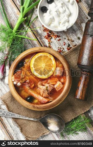 National Ukrainian soup Solyanka. Traditional solyanka with smoked meats in wooden plate