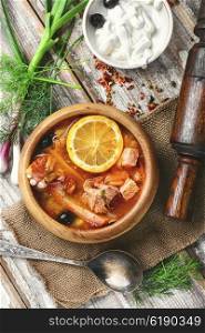 National Ukrainian soup Solyanka. Traditional solyanka with smoked meats in wooden plate