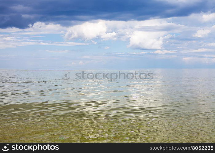 natural background - calm green water of Azov Sea and blue sky with white and rain clouds. Temryuk bay, Golubitskaya resort, Taman peninsula, Kuban, Russia