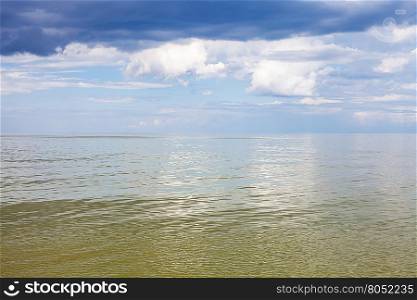 natural background - calm green water of Azov Sea and blue sky with white and rain clouds. Temryuk bay, Golubitskaya resort, Taman peninsula, Kuban, Russia