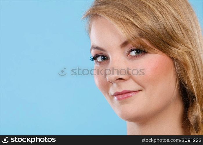Natural beauty concept. Closeup portrait of beautiful attractive blonde woman smiling. Studio shot on blue background.. Closeup portrait of beautiful attractive woman smiling