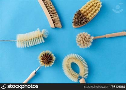natural cleaning stuff, sustainability and eco living concept - different brushes with wooden handles on blue background. different cleaning brushes on blue background