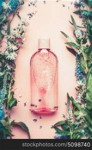 Natural Cosmetic product bottle on pink pale background with plant and flowers, top view, copy space. Floral cosmetics, botanical fragrance concept.