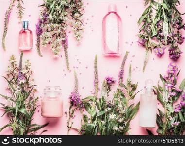 Natural cosmetic products setting with various bottles and fresh herbs and flowers on pink background, top view, flat lay. Beauty, skin, hair or body care concept