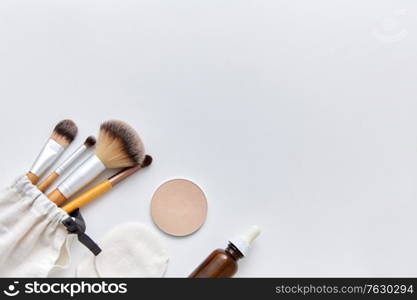 natural cosmetics and eco living concept - wooden make up brushes, cotton pads and swabs, eye shadows and essential oil or serum on white background. make up brushes, cosmetics and cotton swabs