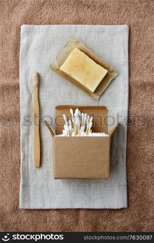 natural cosmetics, sustainability and eco living concept - wooden toothbrush, handmade soap cotton swabs on canvas. wooden toothbrush, handmade soap cotton swabs
