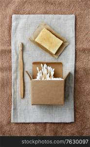 natural cosmetics, sustainability and eco living concept - wooden toothbrush, handmade soap cotton swabs on canvas. wooden toothbrush, handmade soap cotton swabs