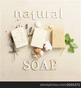 Natural DIY soap bars - lavender, cotton, patchouli - ingredients and wooden letters on natural stone background, top view. Handmade organic soap concept. Natural soap bars - lavender, cotton, patchouli - ingredients and wooden letters on natural stone background, flat lay